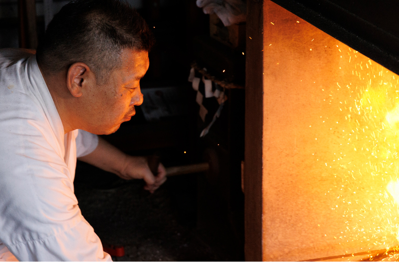 火床の前で刀を作る下島さんの画像